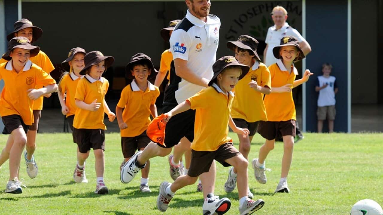 Brisbane Roar midfielder Luke Brattan pays with school children