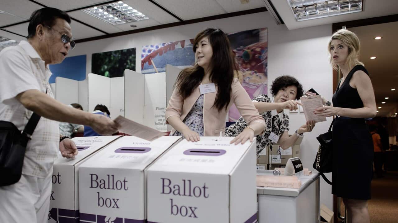 A man (L) casts his ballot at the voting centre of the Australian Consulate-General in Hong Kong on August 27, 2013.