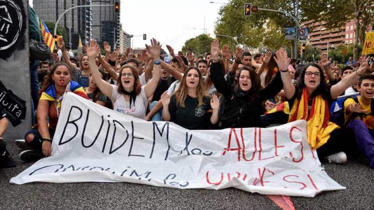 University students hold banner and block traffic during a demonstration against the position of the Spanish government on the referendum on self-determination in Catalonia during a university students strike on September 28, 2017 in Barcelona.