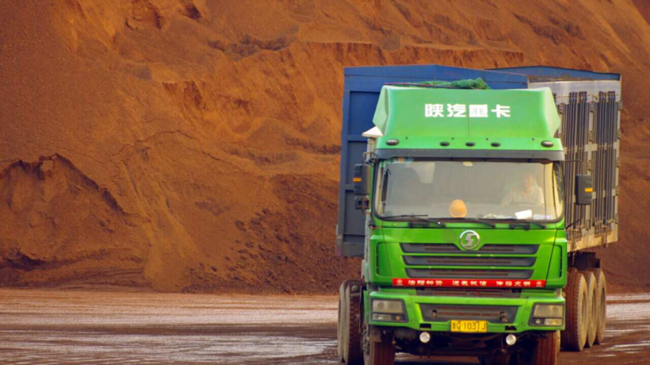 A truck passes by piles of iron ore