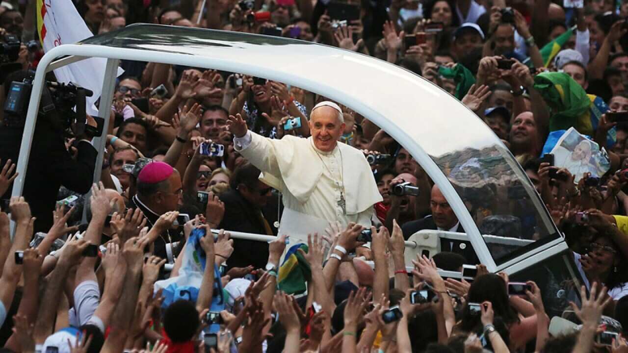 Pope Francis waves to the crowd while departing the Metropolitan Cathedral in the Popemobile after arriving in Rio. (Getty)