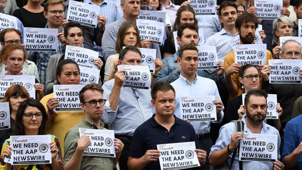 Journalists, photographers and staff hold signs in support of AAP staff