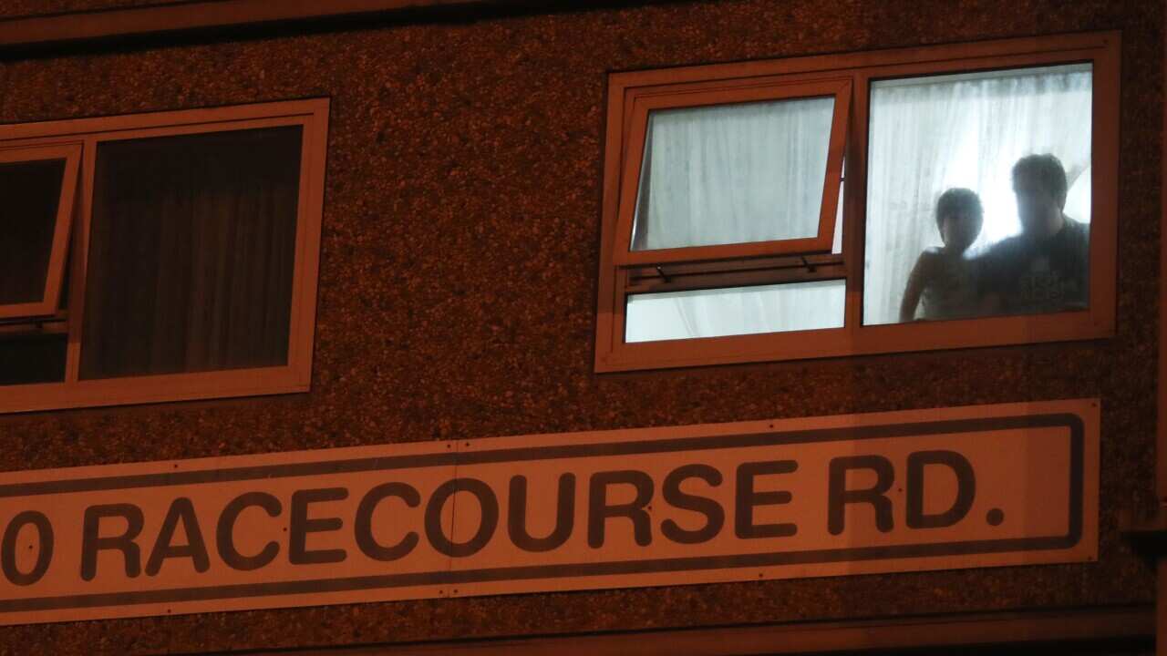 Residents watch from their window as police enforce a lockdown at public housing towers on Racecourse Road in Flemington, Melbourne.