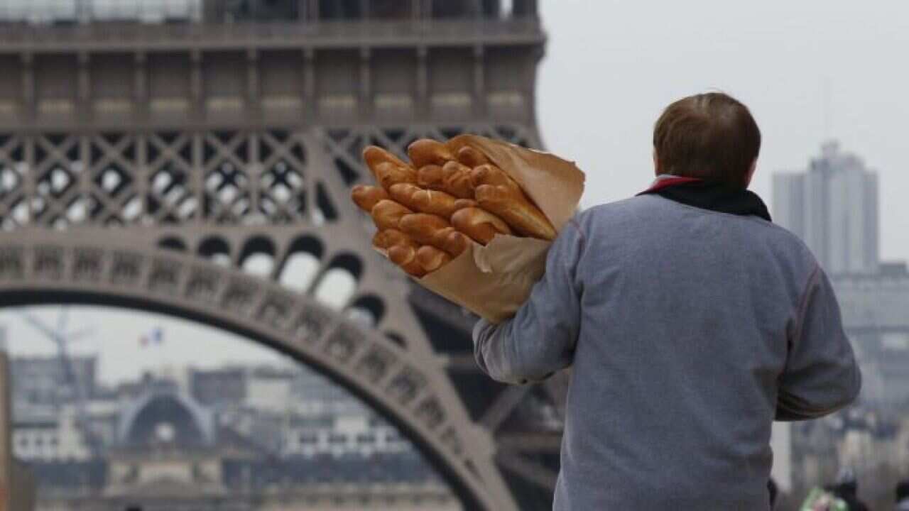 A man carries loaves of French bread.
