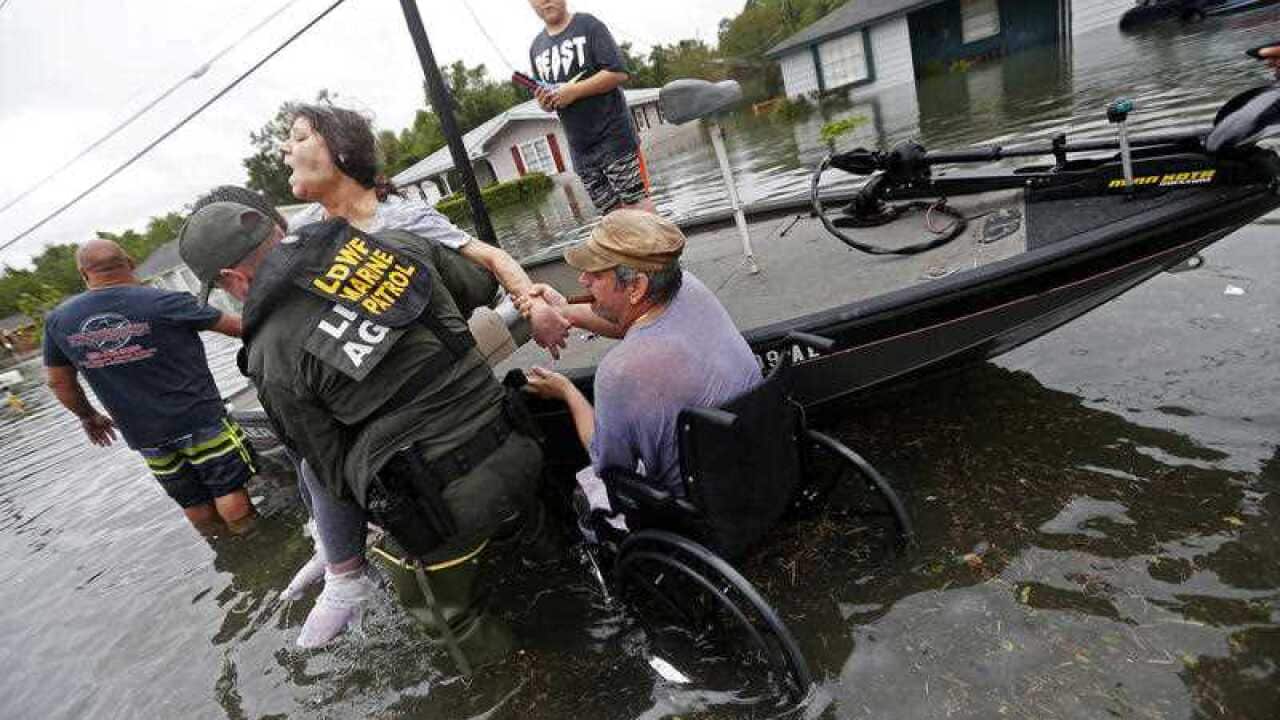 Members of the Louisiana Department of Wildlife and Fisheries help rescue Mike Henry, right, and his partner Rosemarie Carpenter during flooding
