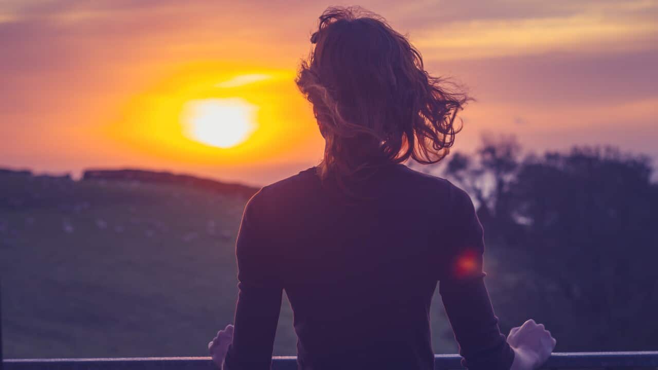 Woman admiring sunset from her balcony