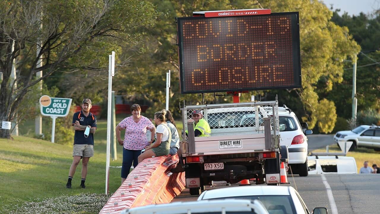 People talk to each other over the barriers at the QLD-NSW border (AAP)