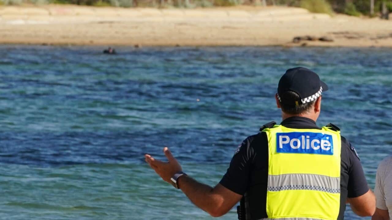 Police officers inform beachgoers that the beach is closed at Brighton Beach in Melbourne.