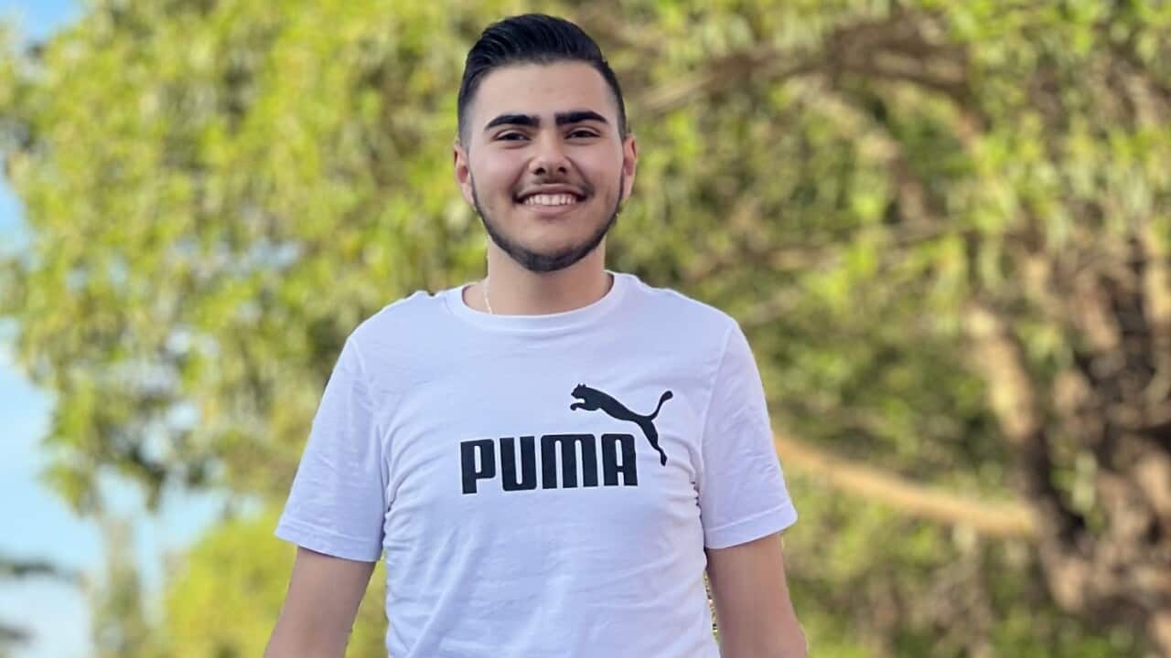 A young man in a white Puma T-shirt is walking on the street.