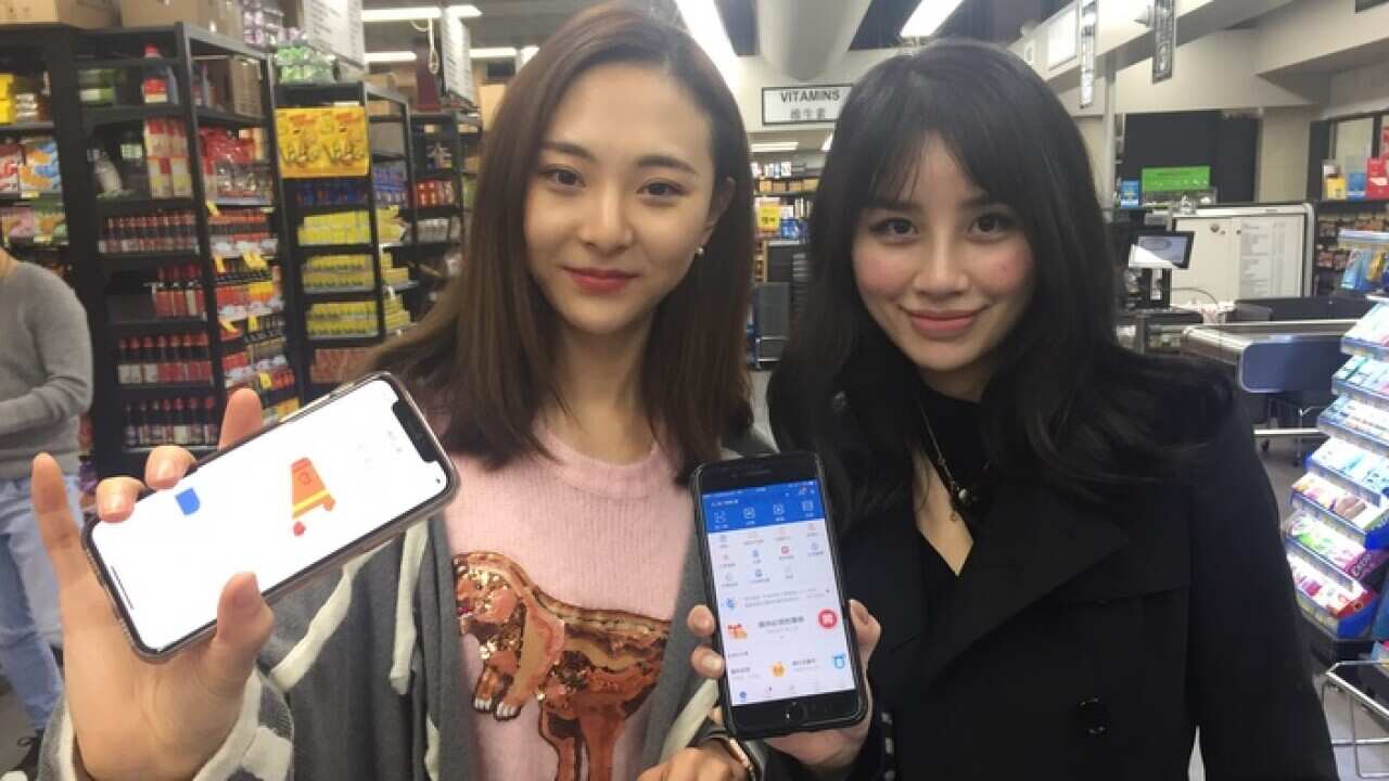 دو دانشجوی چینی که از اپلیکیشن های پرداخت از طریق موبایل برای خرید استفاده می کنند