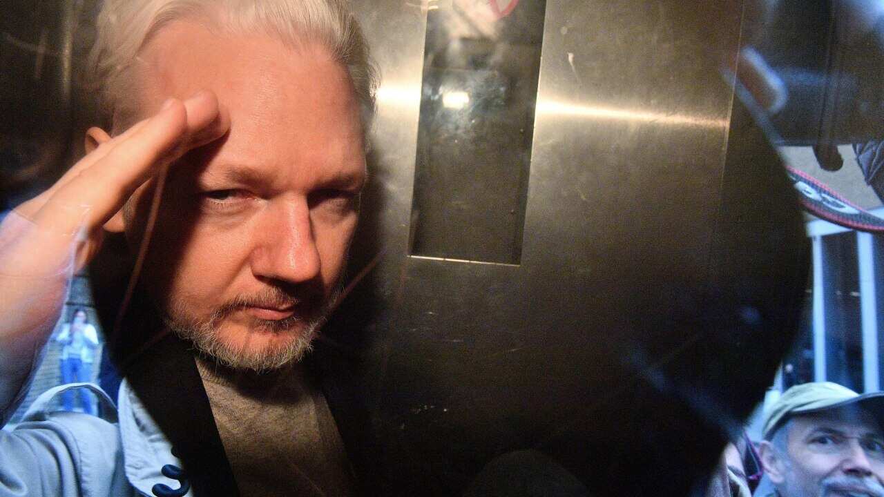 WikiLeaks founder Julian Assange gestures from the window of a prison van.