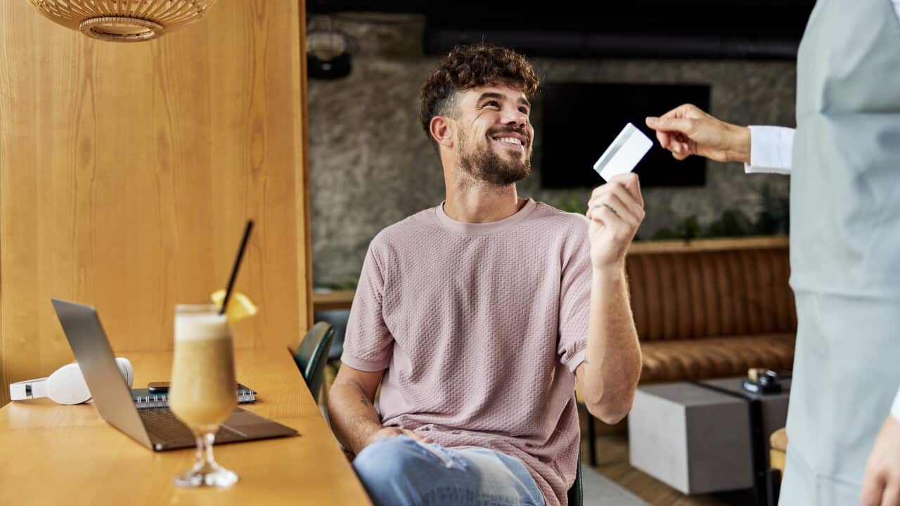 Happy man paying the bill in a café with a credit card.