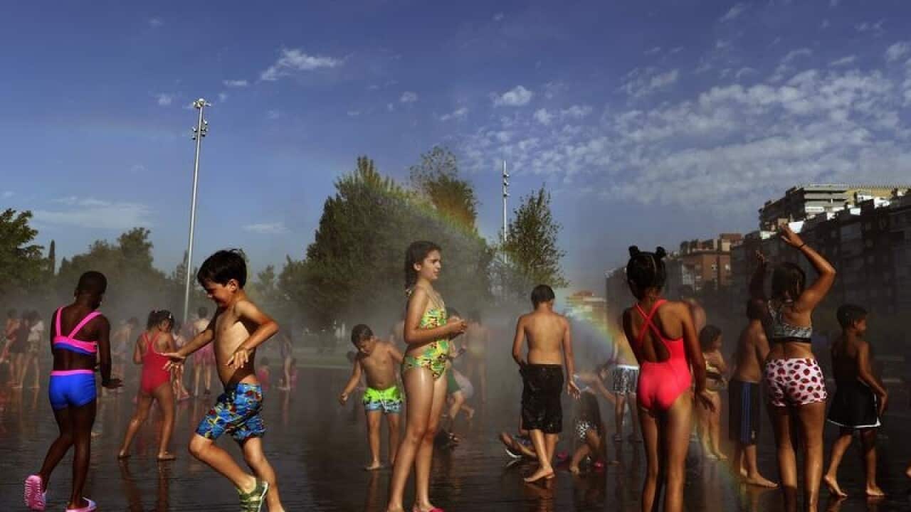 Children cool off at an urban beach in the middle of Madrid