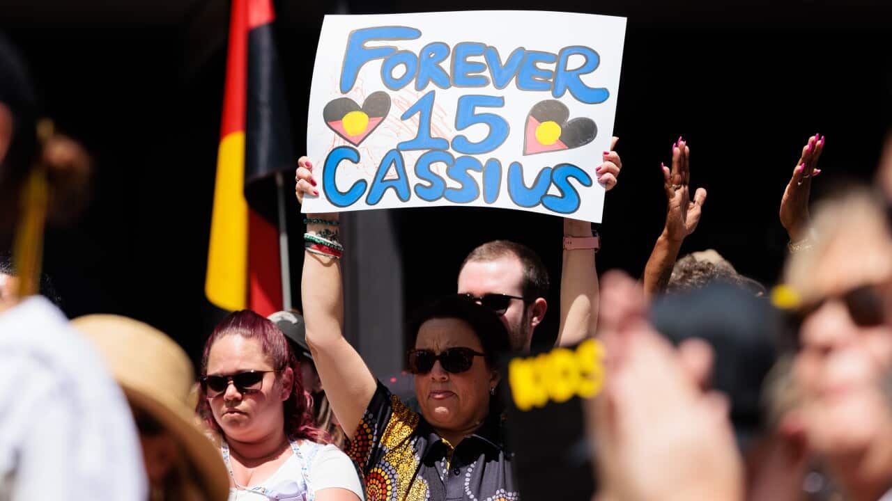 A woman hold up a sign during a rally for Cassius Turvey