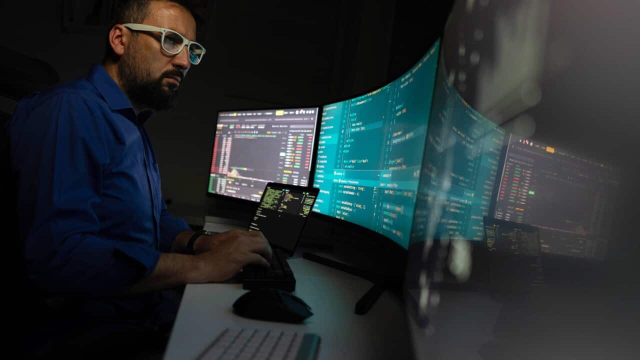 Man working on multi displays professional environment.