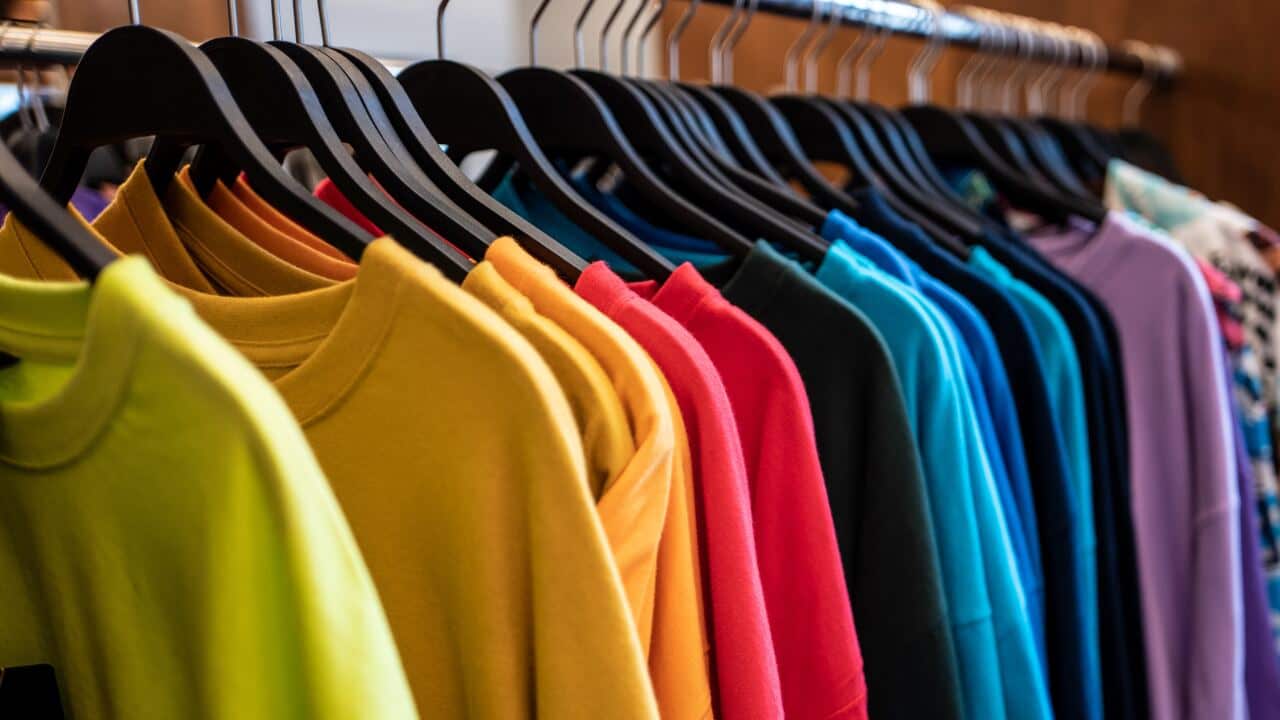 A rail of brightly-coloured t-shirts on coathangers