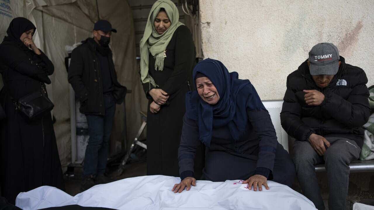 A woman mourns a dead relative wrapped in white shroud