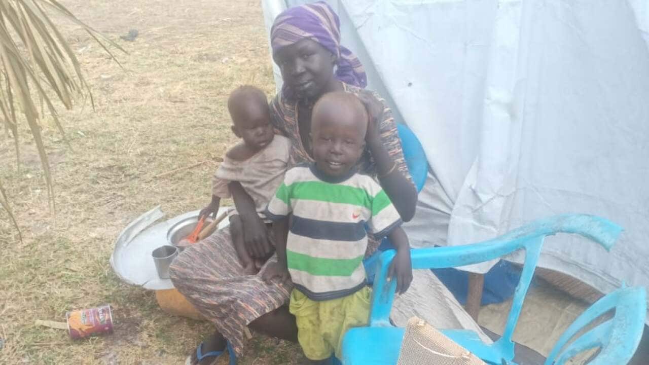Monica and her children outside their tarp shelter