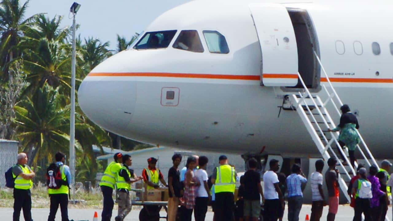 A group of asylum seekers board a plane at Cocos Island