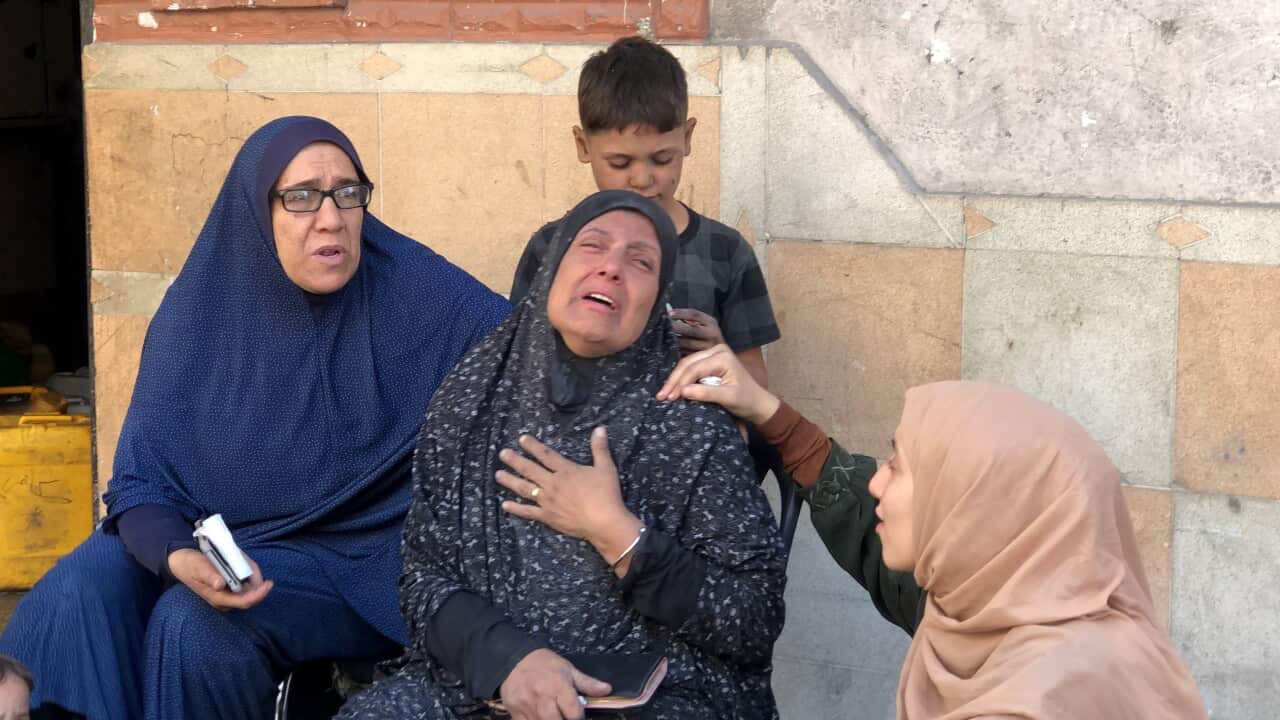 A woman crying surrounded by women comforting her