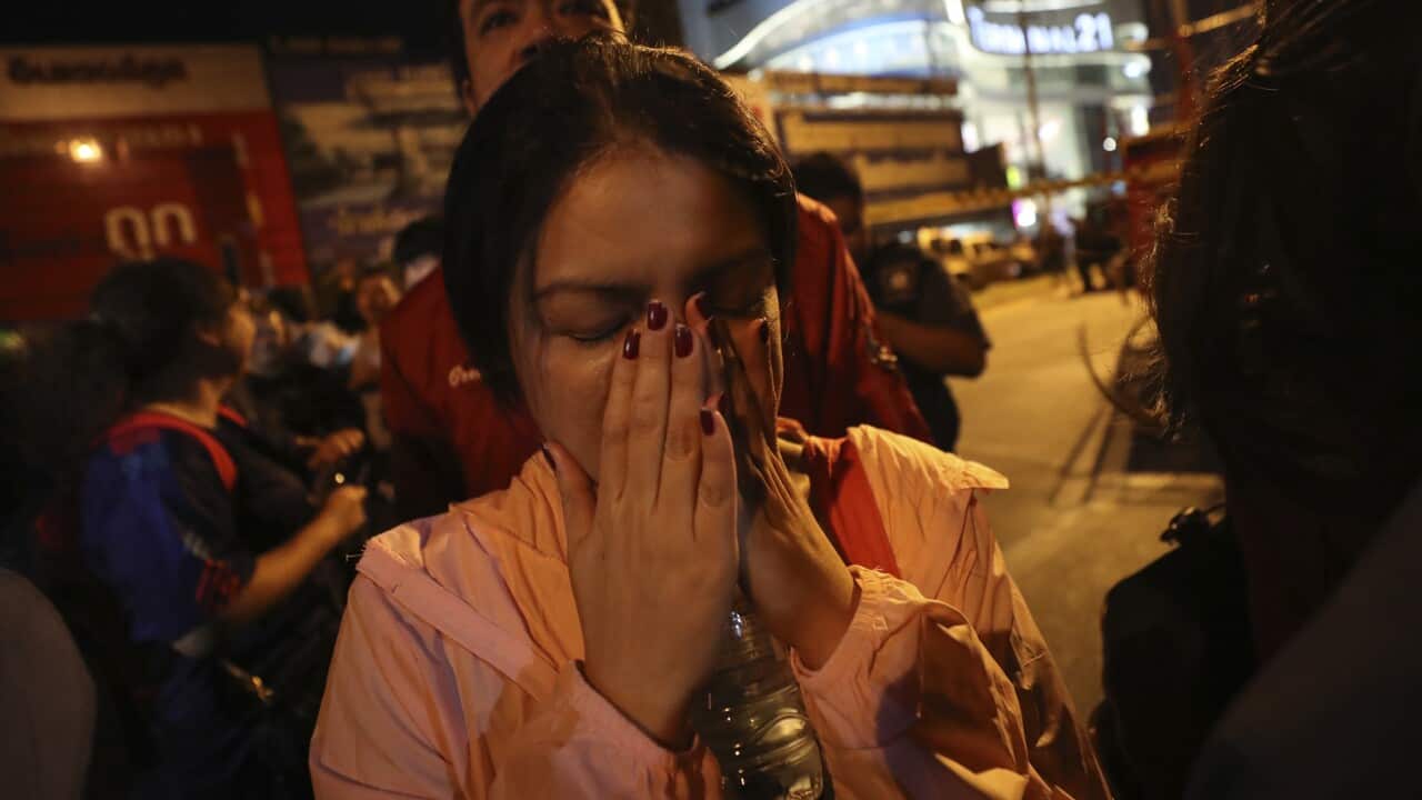 A woman who was able to get out of Terminal 21 Korat mall gestures with her hands on her face in Nakhon Ratchasima.