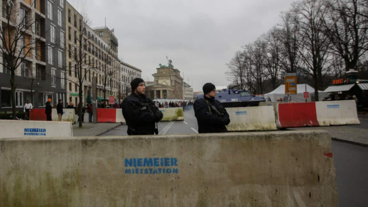 Armed police officers stand behind concrete blocks for protection near the Brandenburg Gate in Berlin, Friday, Dec. 23, 2016,