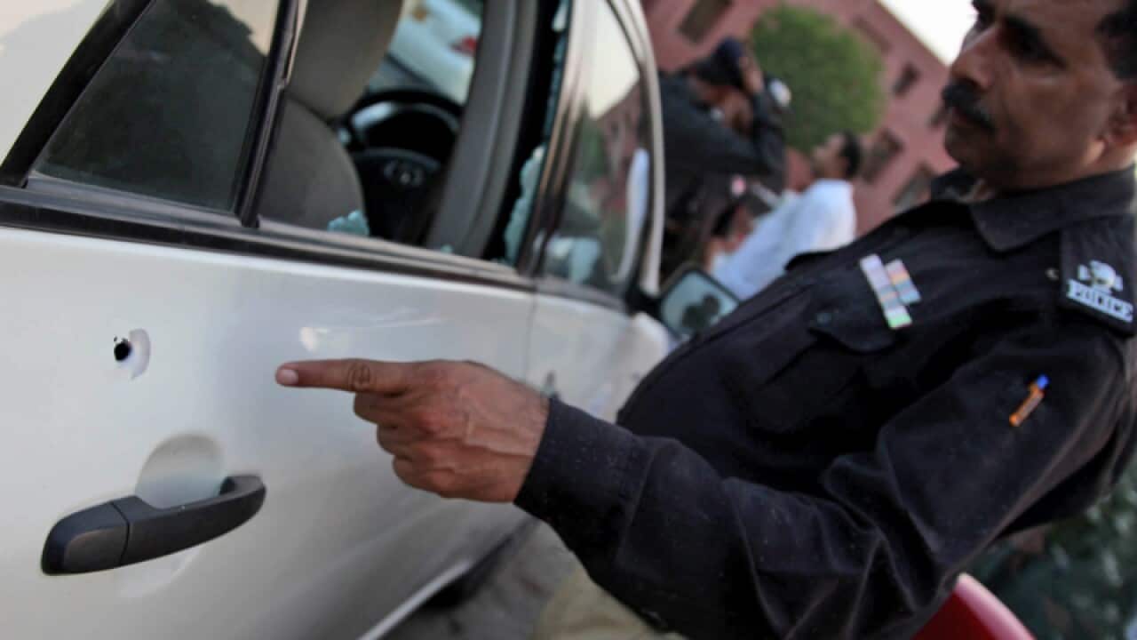 A police officer points at a bullet hole in the vehicle of Hamid Mir