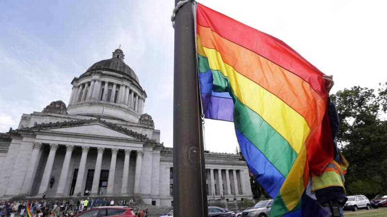 A state worker unfurls a rainbow flag in Washington state.