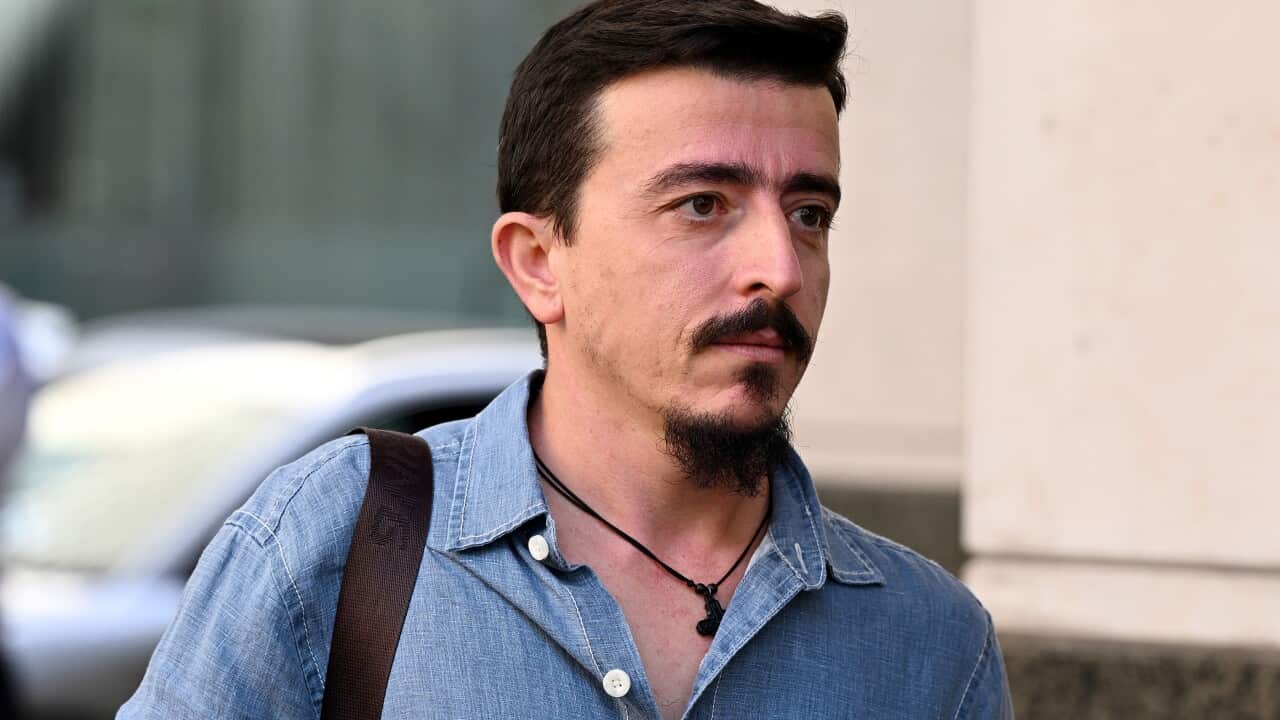 A man in a denim blue shirt walking.