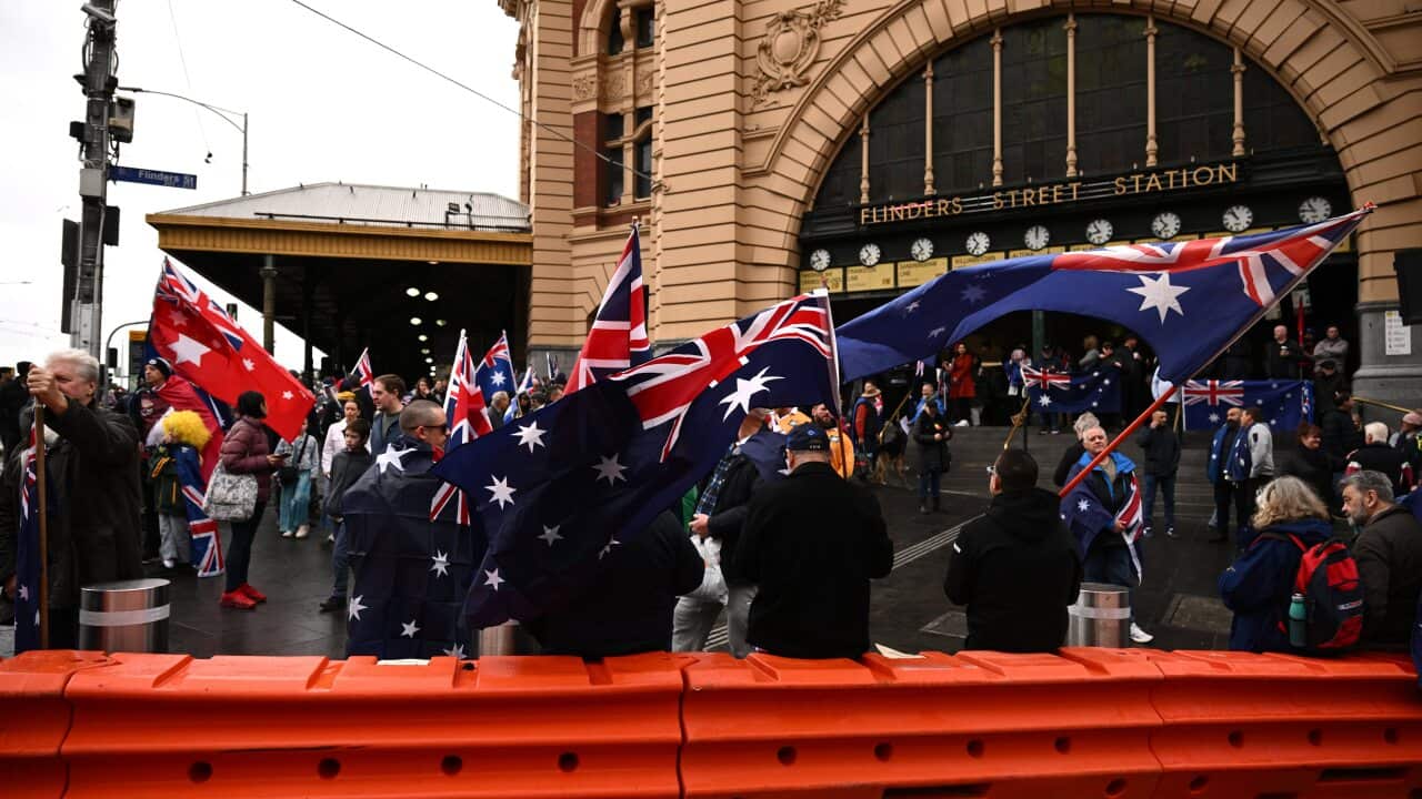 A group of protesters, some waving Australian flags, outside Flinders Street Station.