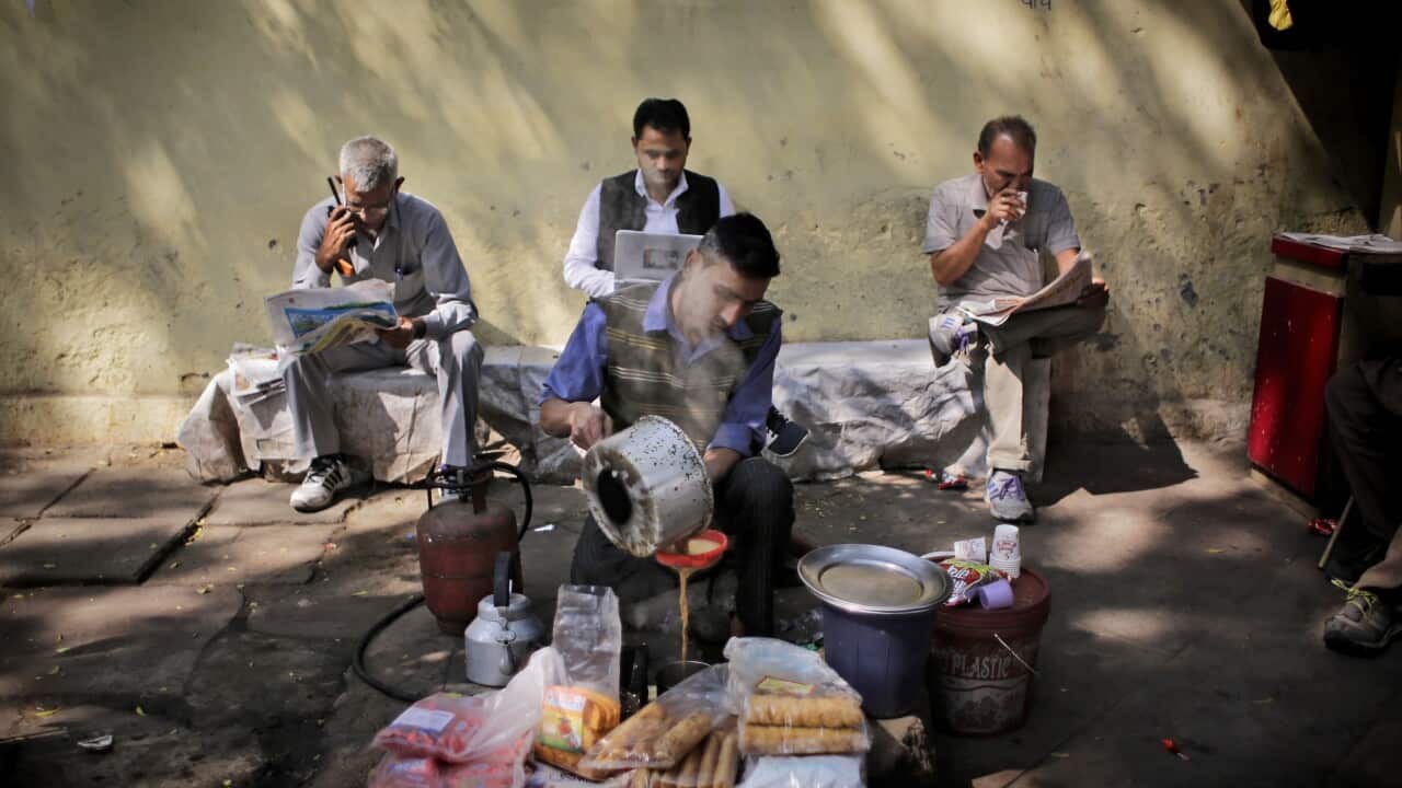An Indian roadside tea vendor prepares tea for people reading newspapers in New Delhi, India, Tuesday, March 1, 2016.