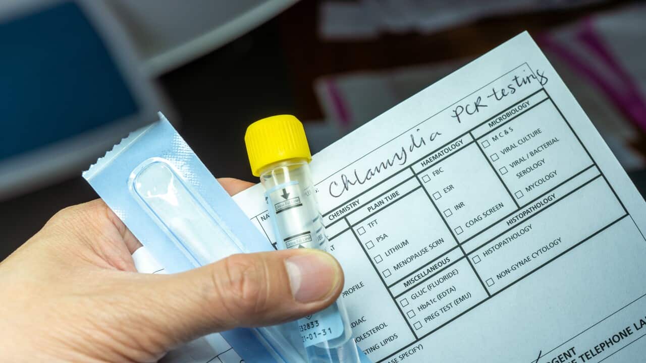 A hand holding a vial with a yellow cap and a piece of paper with printed words on it