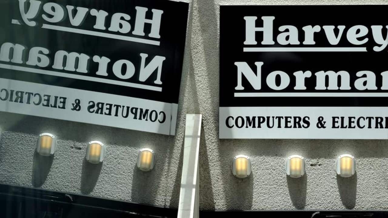 A Harvey Norman store sign reflected in a window in Sydney.