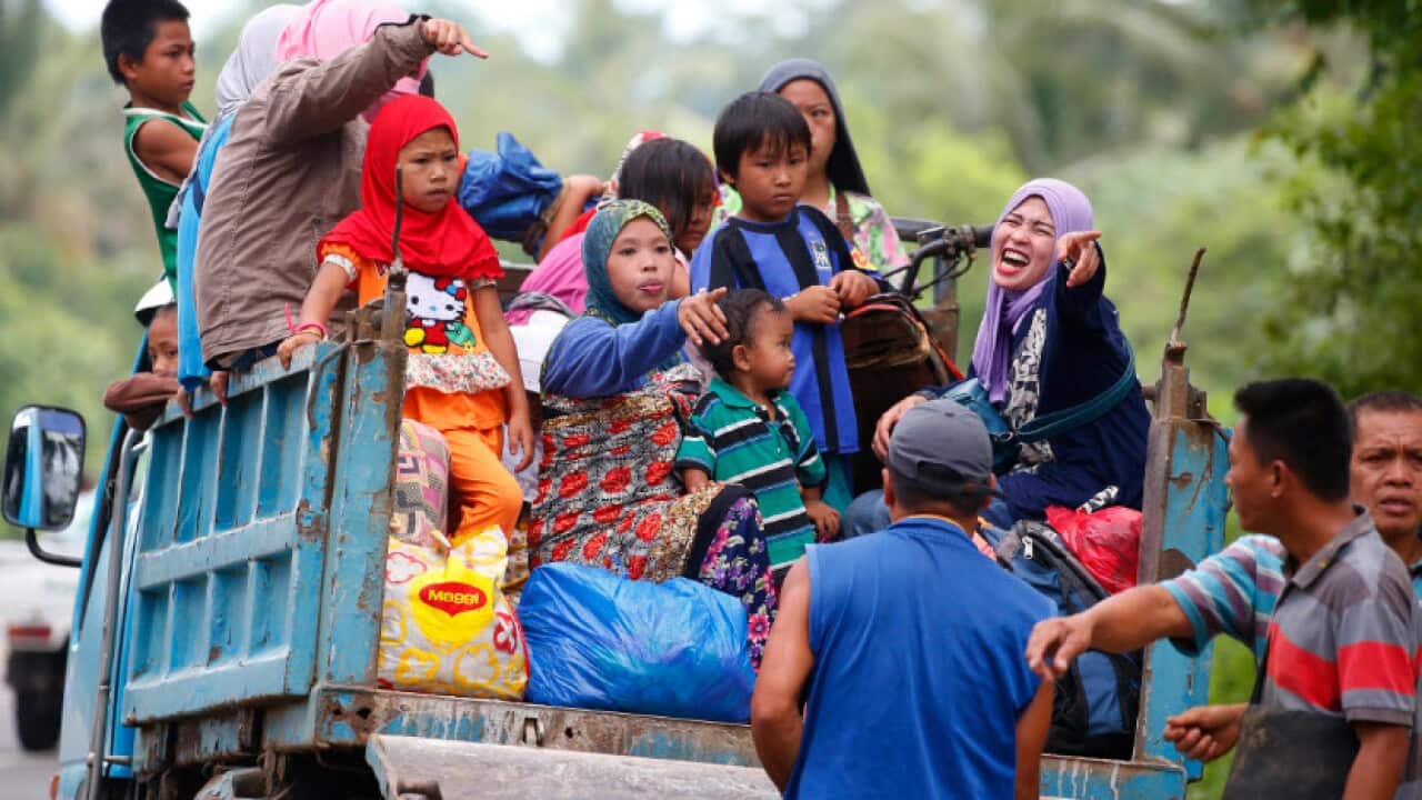 Displaced residents fleeing by a truck to safer areas stop by a roadside as government troops battle with Muslim militants