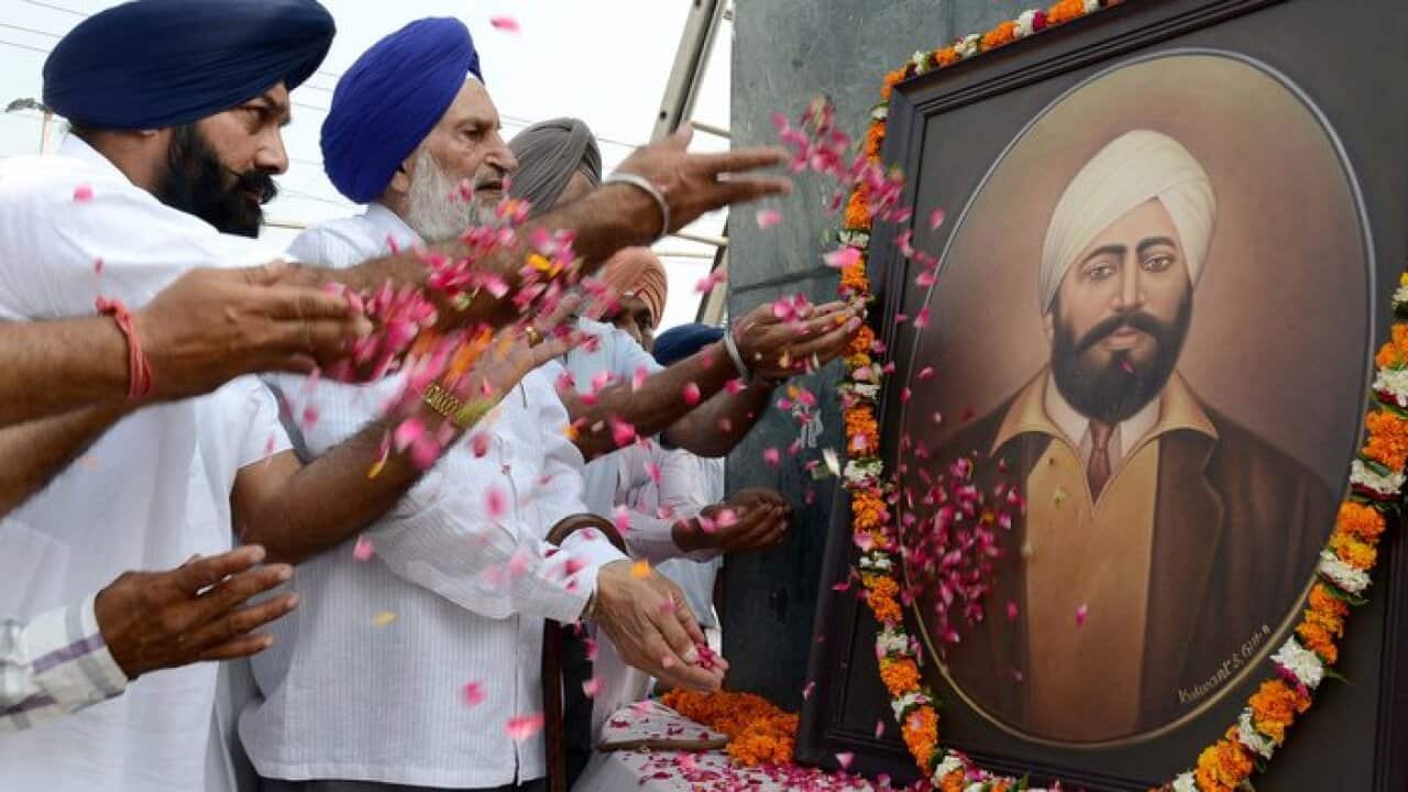 Indian members of the Kamboj Sabha organisation shower flower petals on a portrait of Udham Singh