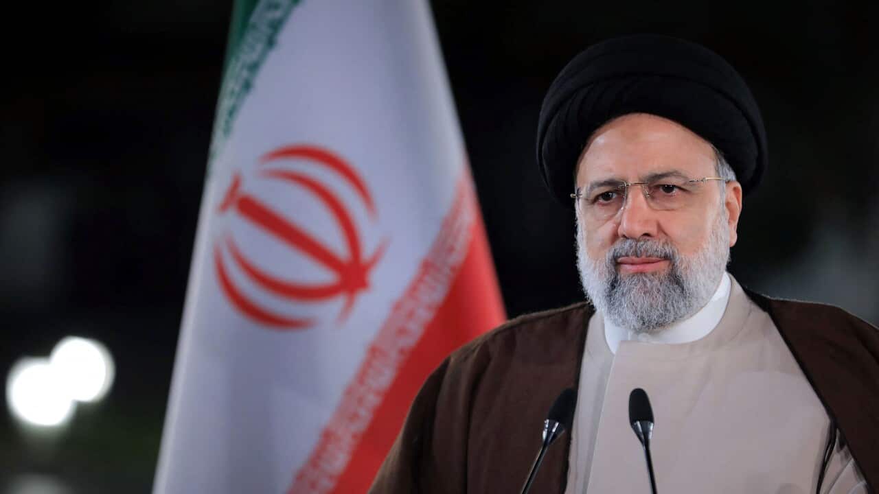 Ebrahim Raisi giving a speech at a podium with Iran flag in background
