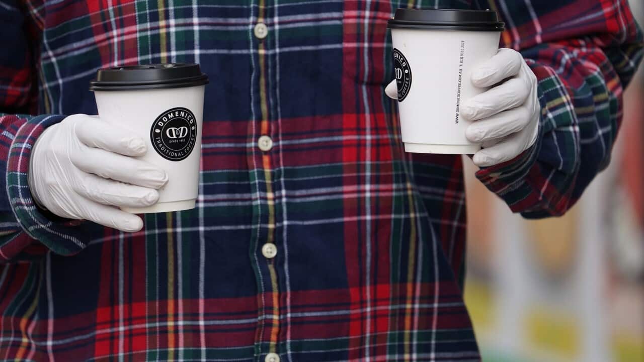 A member of the public is seen wearing gloves while leaving a cafe in Melbourne.