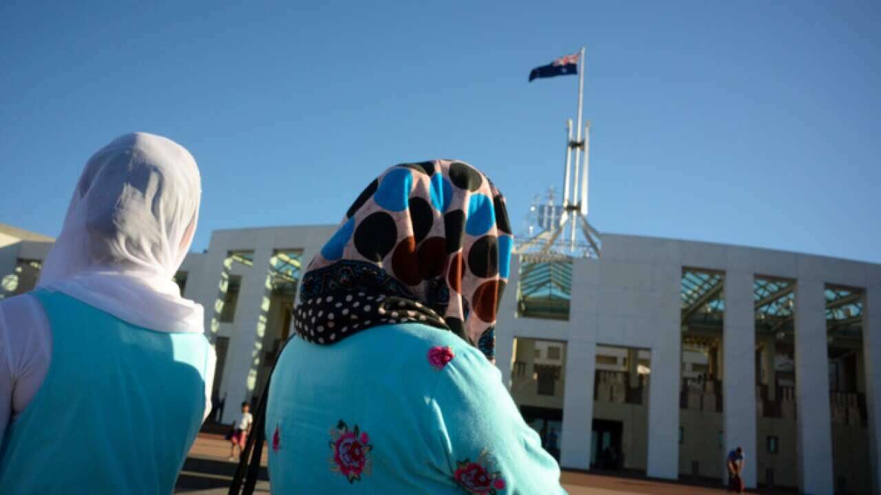 Visitors of Afghan nationality wearing hijabs are seen outside Parliament House in Canberra.