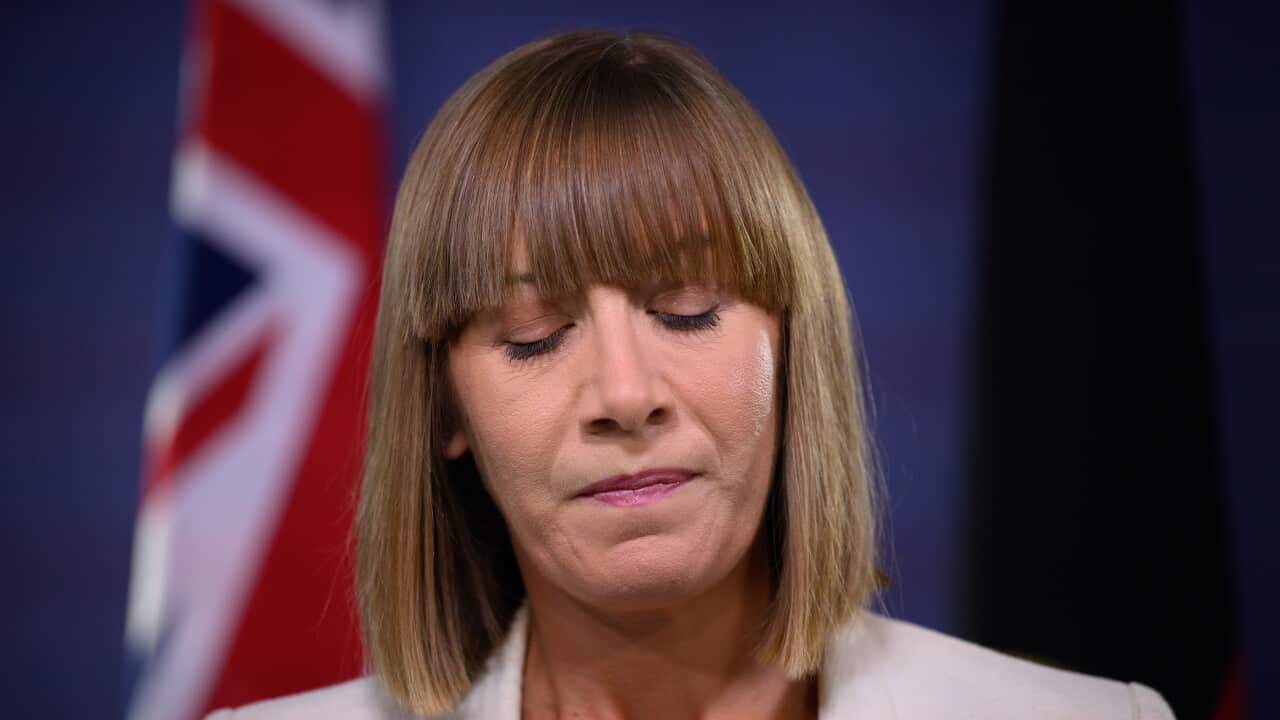 A woman in a white blazer looking down