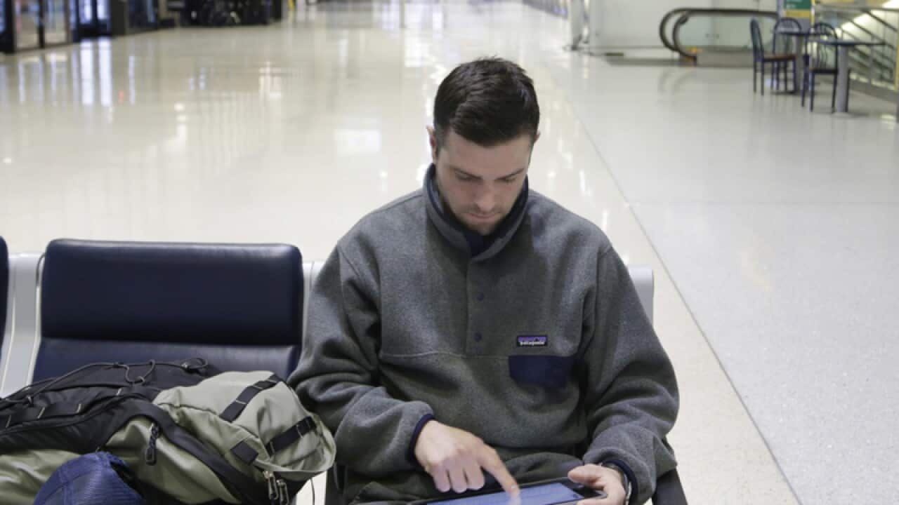 A passenger uses his tablet as he waits for his flight