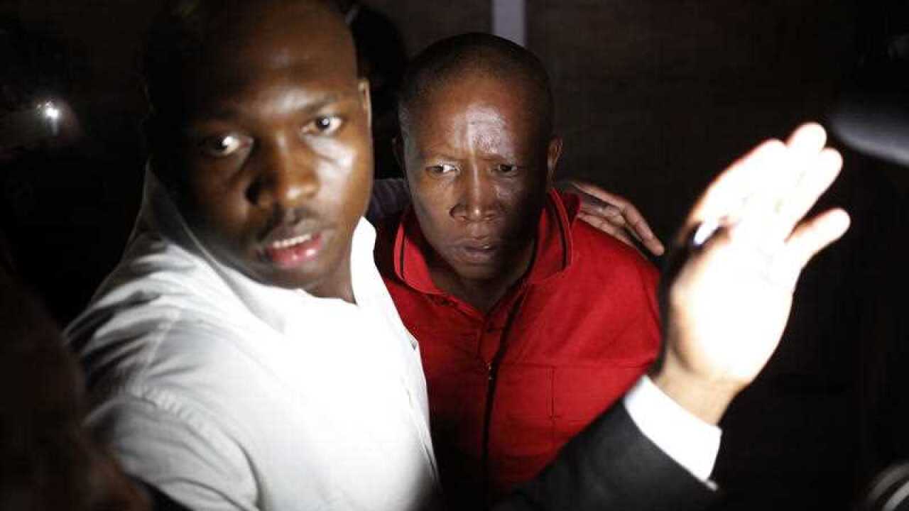 South African political leader of the EFF Julius Malema, center, is guarded, after he was removed from the Parliament in Cape Town, South Africa,