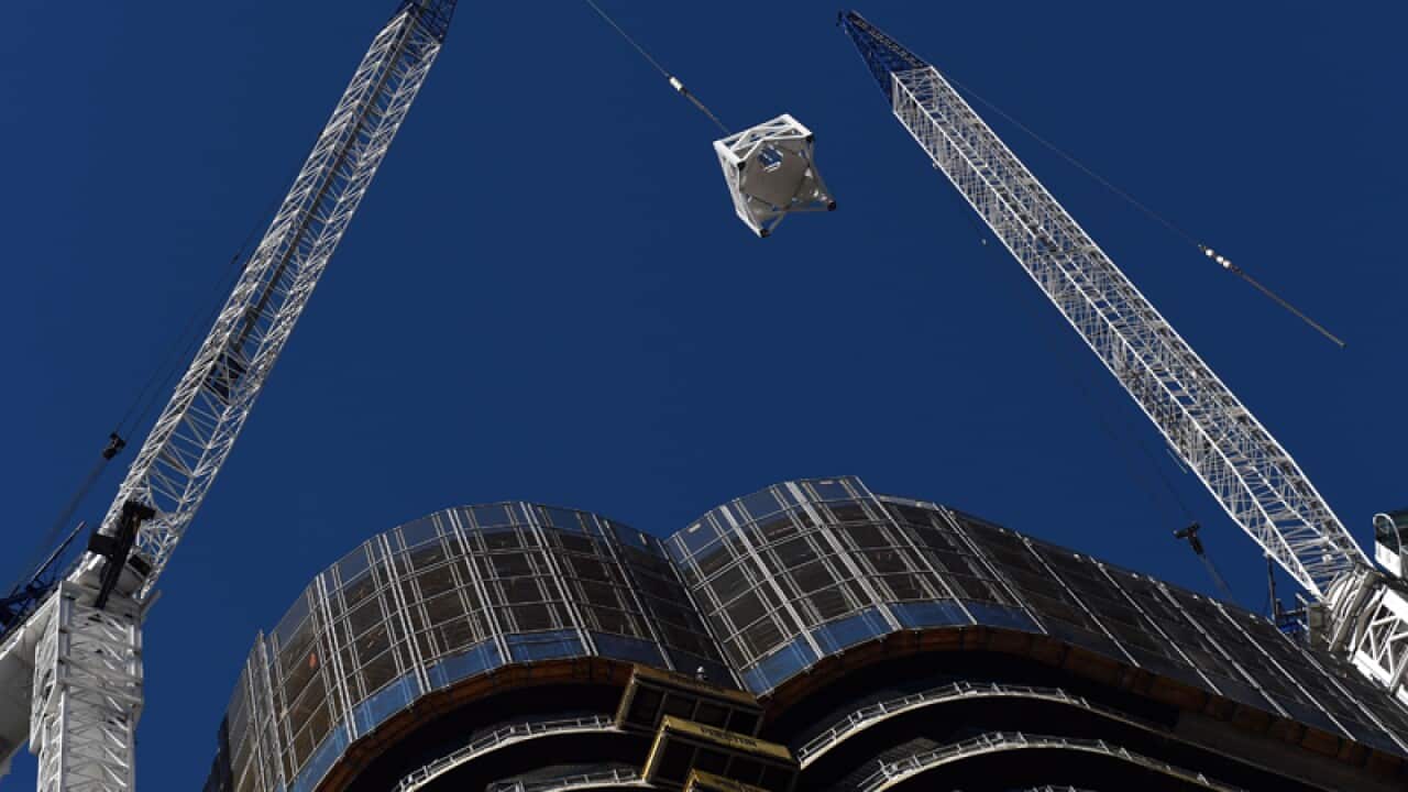 A crane lifts materials onto a building.