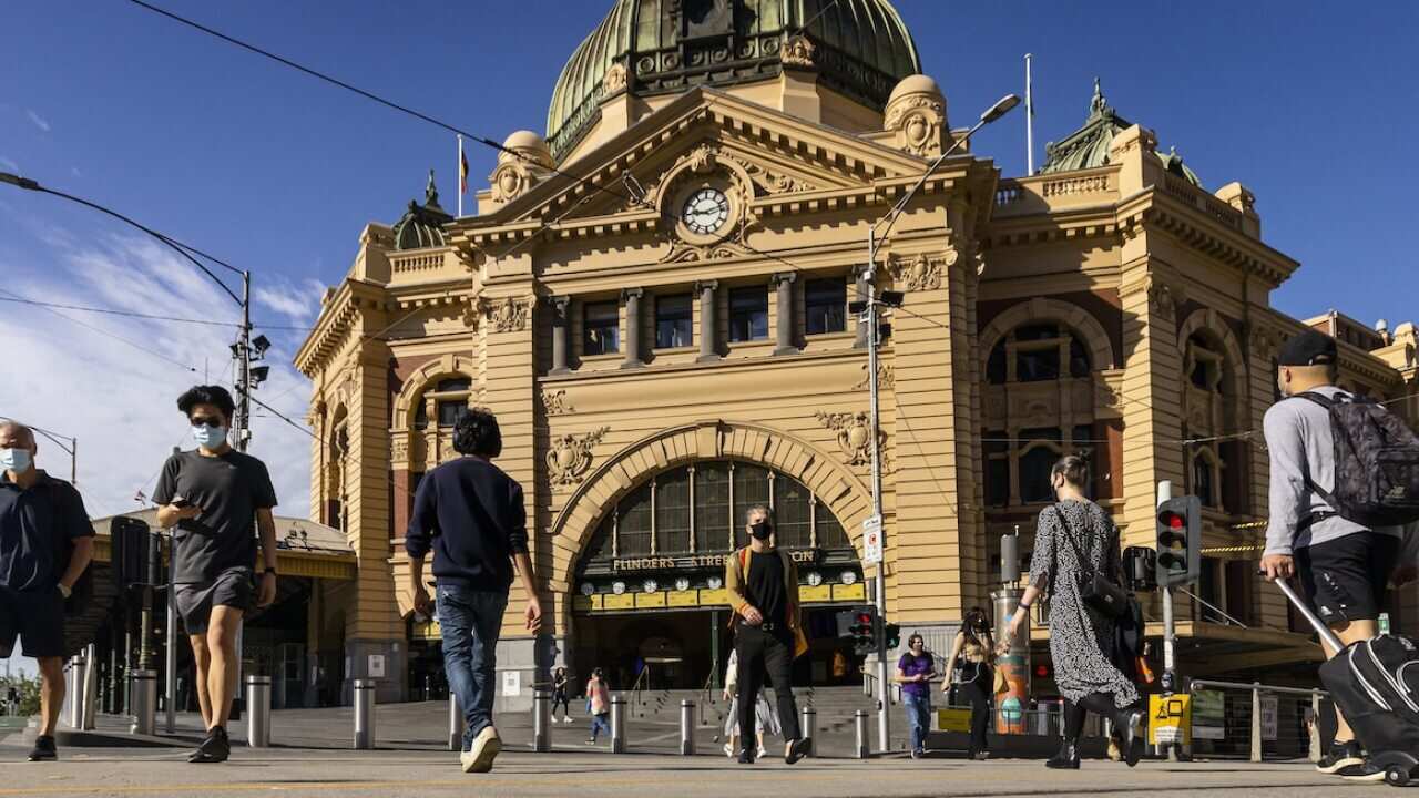 People are seen walking across Flinders Street in Melbourne, Friday, October 22, 2021.
