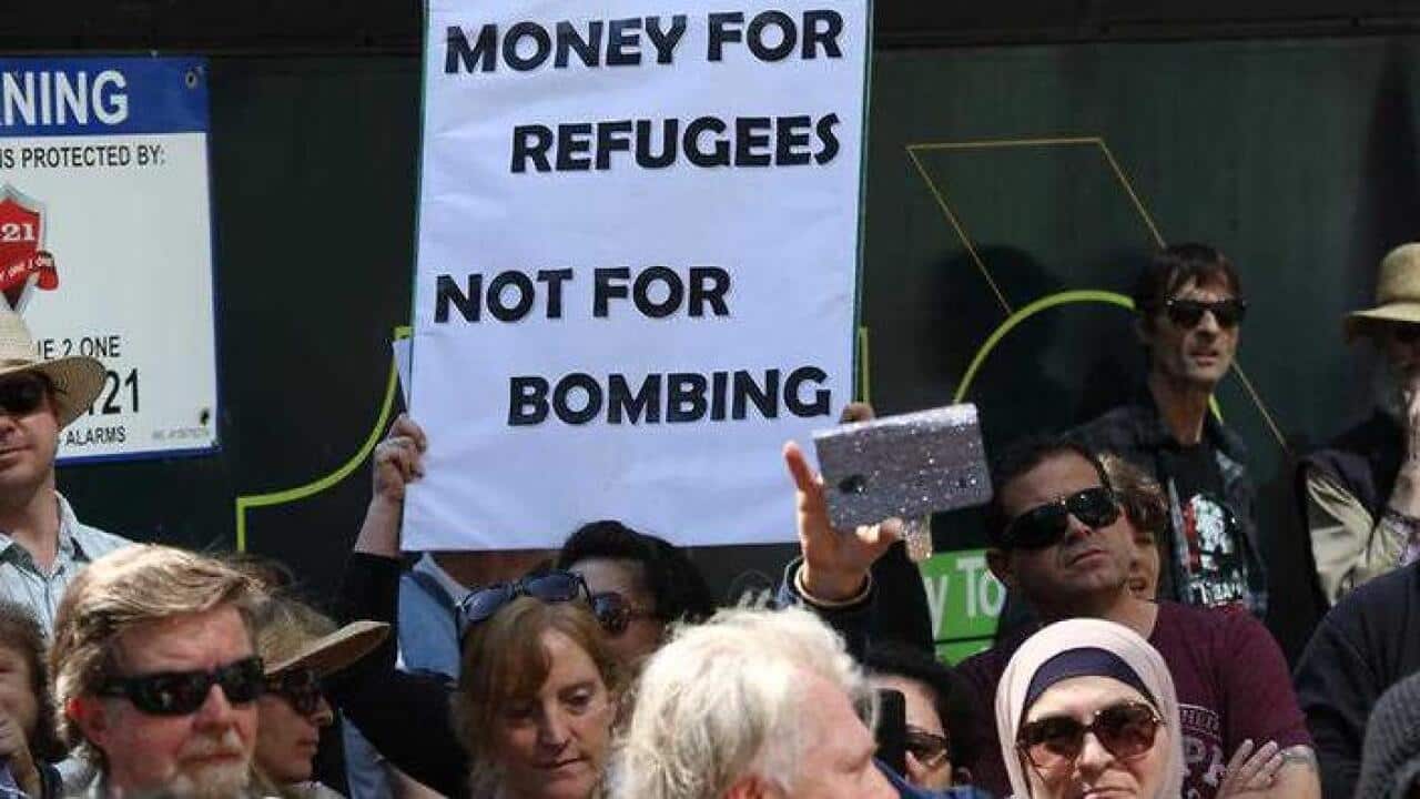 A sign calls for money for refugees as Hands off Syria protesters gathered outside Sydney Town Hall on September 13, 2015 to protest the government's bombing against Islamic State targets in Syria. (AAP)