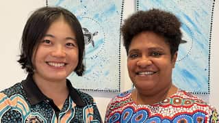 A Chinese woman in a black shirt with First Nations art, next to a First Nations woman in a shirt also with First Nations art