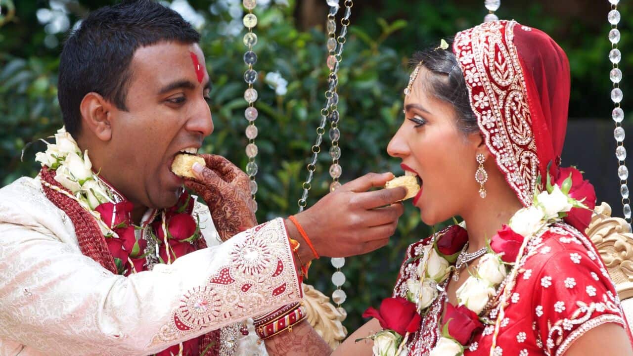 Bride and Groom feeding wedding cake to each other during an Indian wedding ceremony.