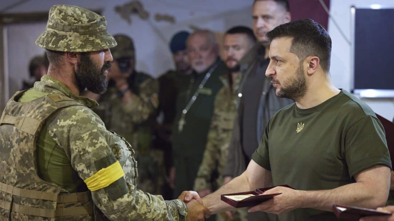 Ukrainian President Volodymyr Zelenskyy gives a soldier an award
