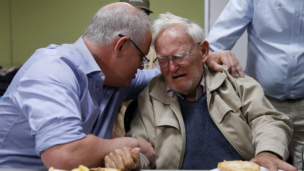 Prime Minister Scott Morrison comforts a man who escaped bushfires during a visit to an evacuation centre on Sunday.