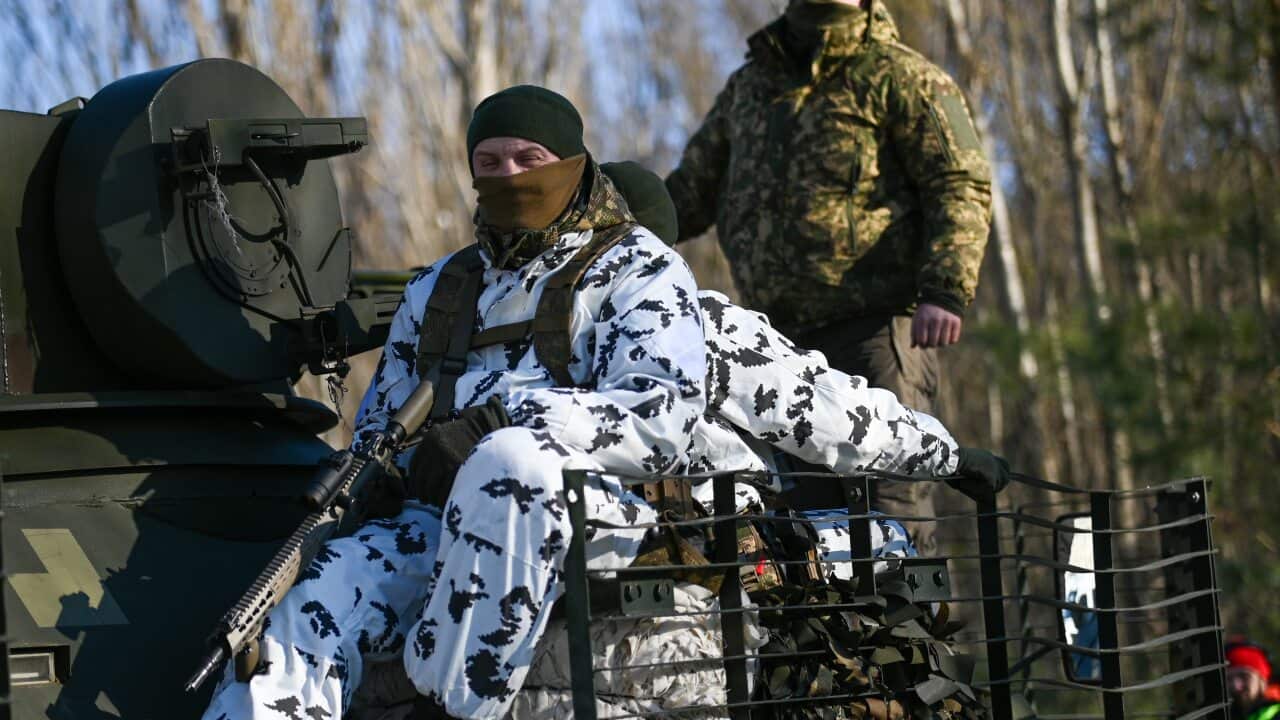 Ukrainian National Guard soldiers ride on top of a BTR-80 armored personnel carrier during an urban warfare exercise.