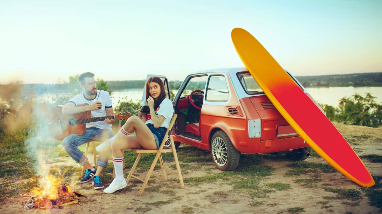 Couple sitting and resting on the beach playing guitar on a summer day near river